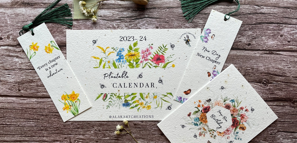 A range of A La KArt Creations plantable greetings cards and gifts, feautring plantable calendars, bookmarks, and greeting cards, laid out on a wooden backdrop.