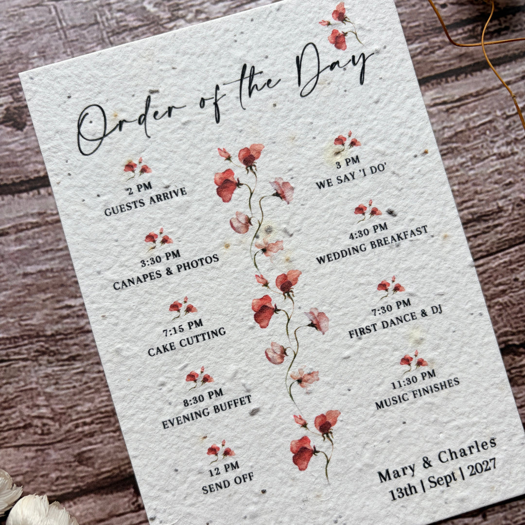 Wedding seed paper order of the day card with floral design on a wooden surface