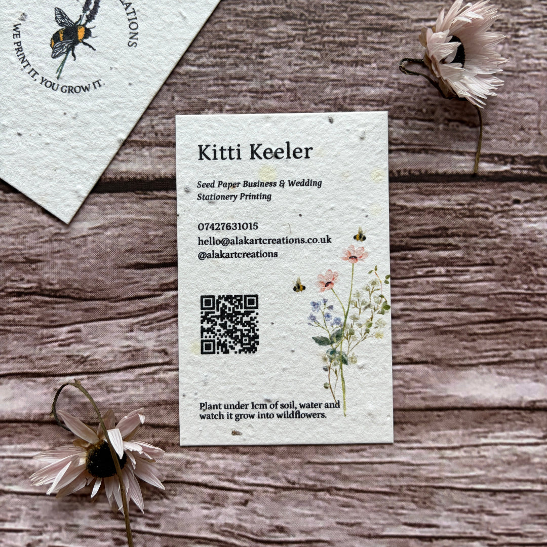 Plantable seed paper business card with floral design on a wooden surface