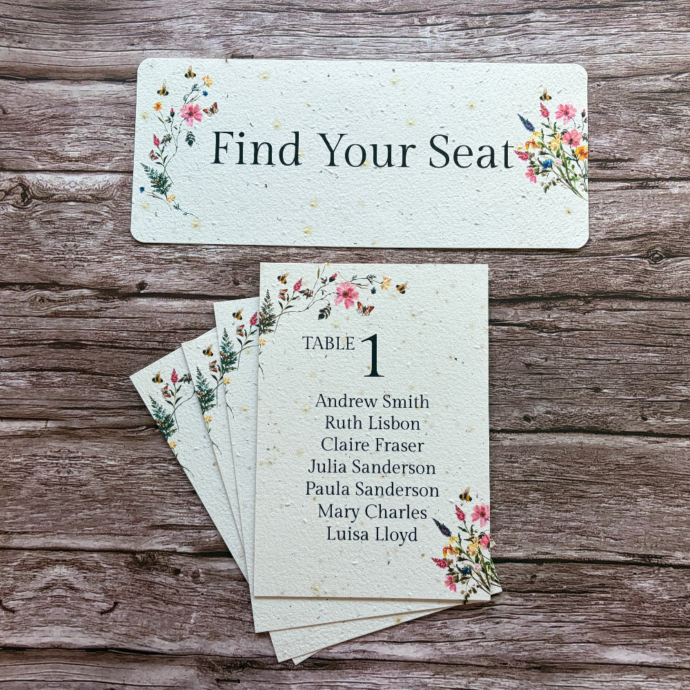Pink meadow plantable sable seating cards with floral designs on a wooden surface