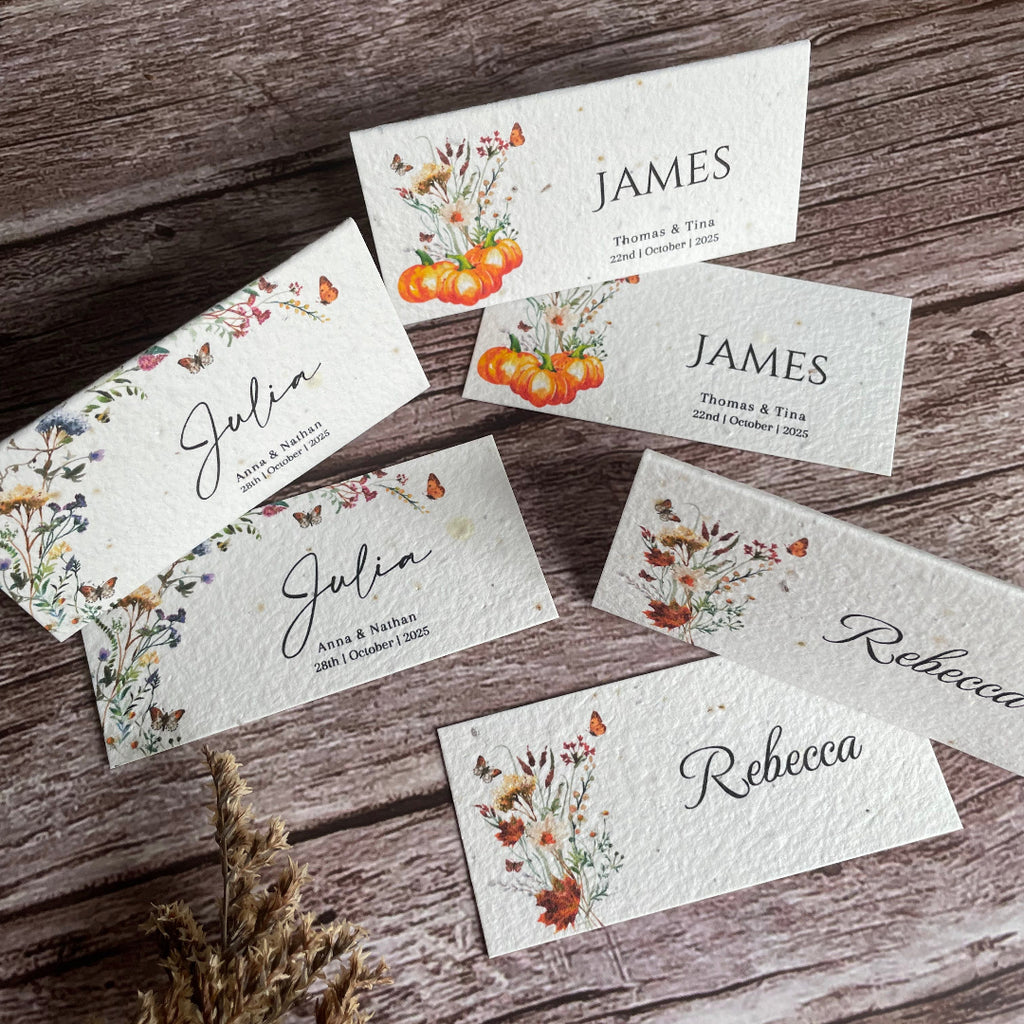 Set of floral guest place cards on a wooden surface with autumn theme