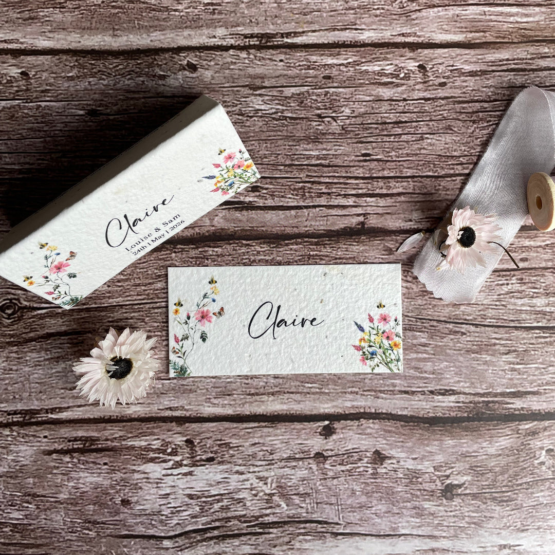Floral seed paper wedding place cards with 'Claire' on a wooden surface