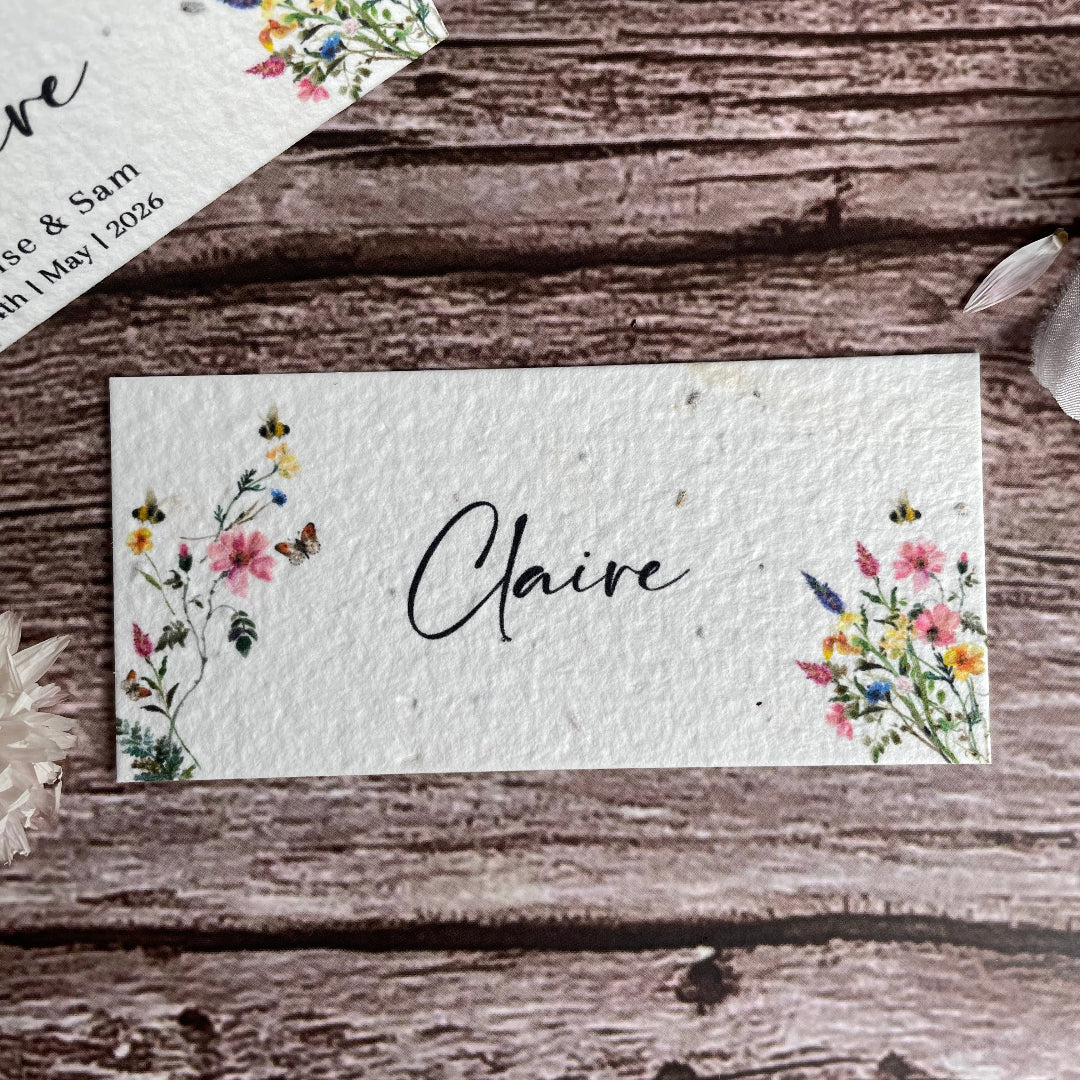 Name card with floral designs and 'Claire' printed on it, placed on a wooden surface.