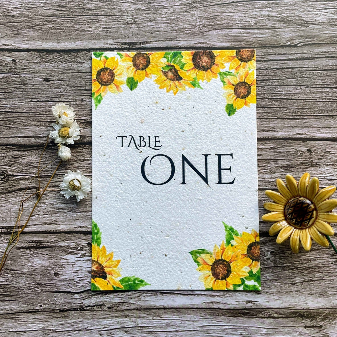 plantable seed paper wedding table number or name cards in sunflower theme, front close-up view with floral design on wooden background, eco-friendly, alakartcreations