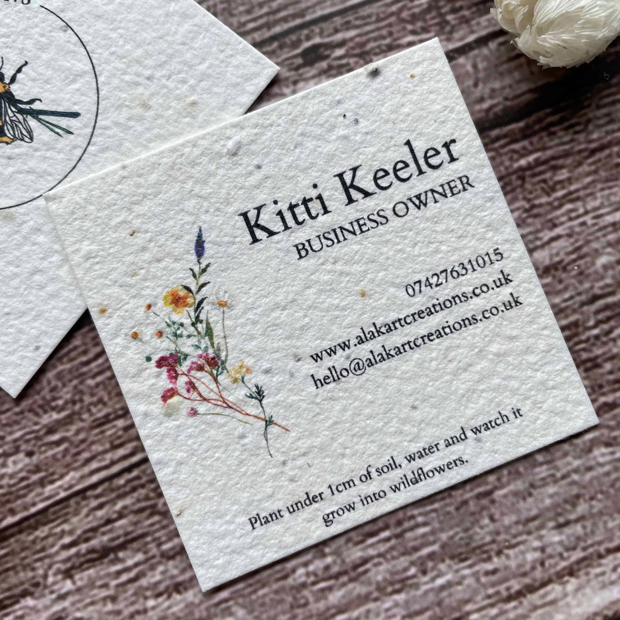 square plantable seed paper business cards with floral design featuring vibrant wildflowers, angled left, alakartcreations