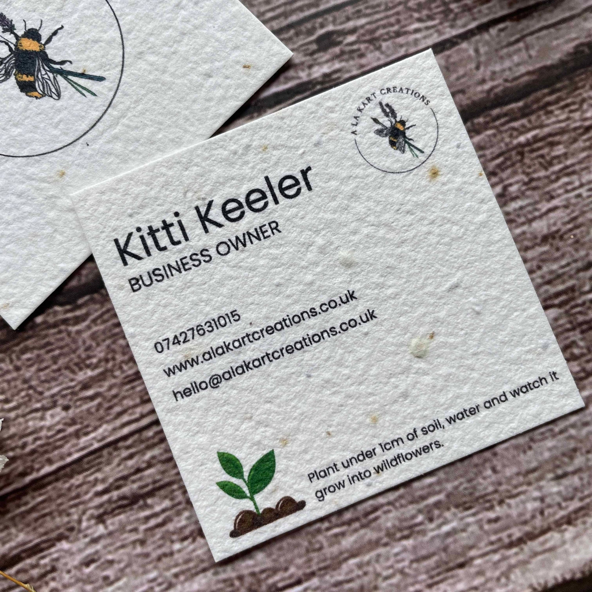 square plantable seed paper business cards with seedling design on front and back, angled left, alakartcreations
