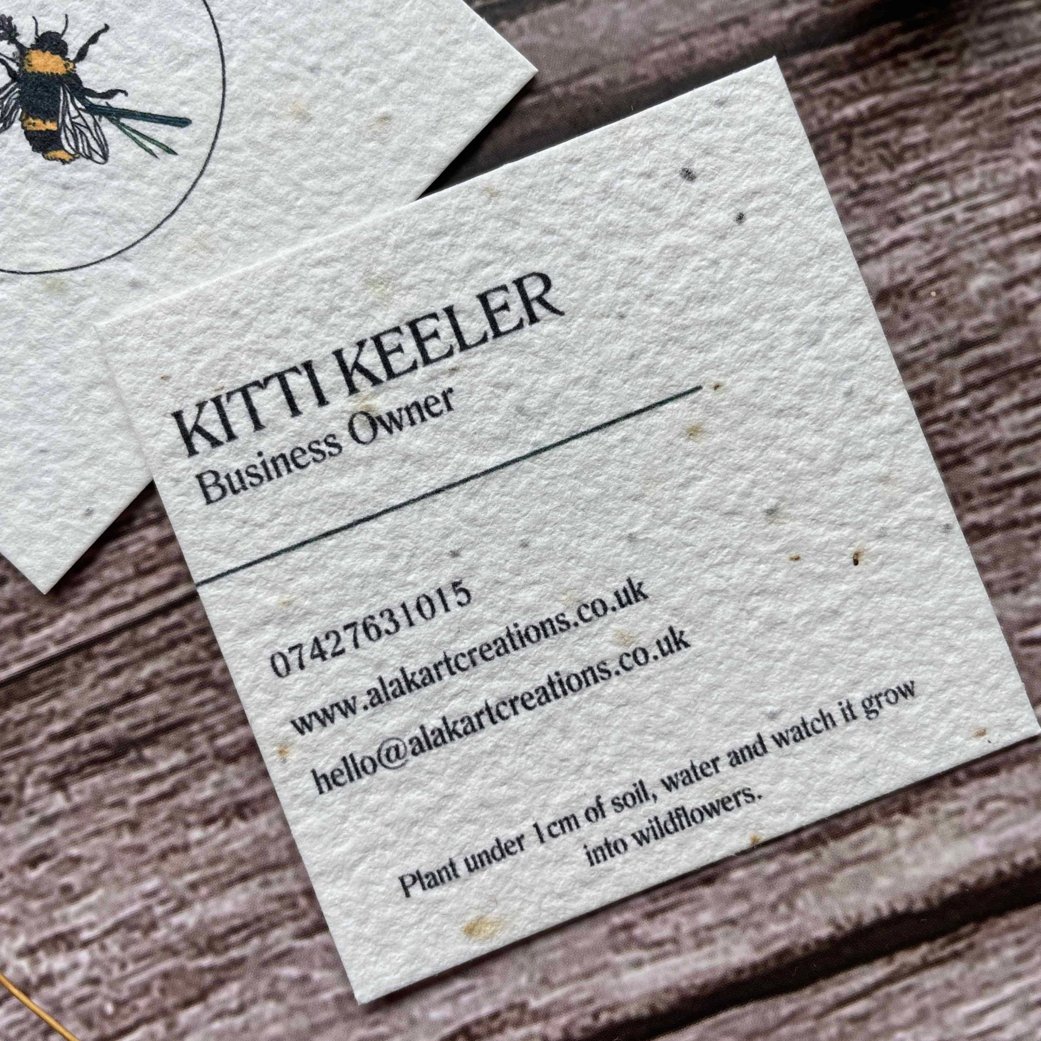 square plantable seed paper business cards with wildflower seeds, angled left showing closeup of custom information, alakartcreations