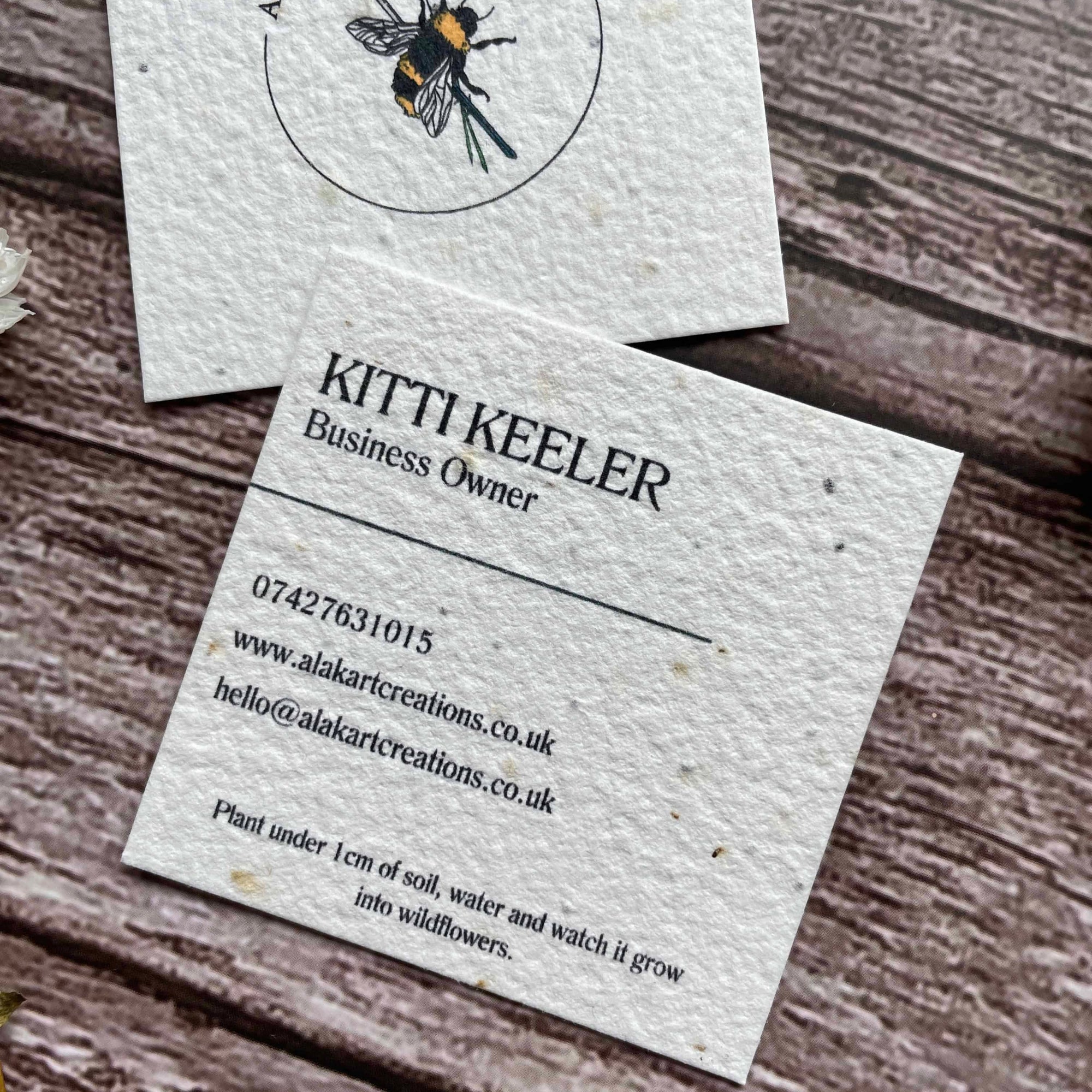 square plantable seed paper business cards with wildflower seeds, angled right showing closeup of custom information, alakartcreations