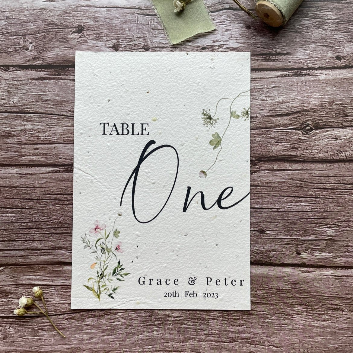plantable seed paper wedding table number/name card with a botanical showing front view, floral design on wooden background
