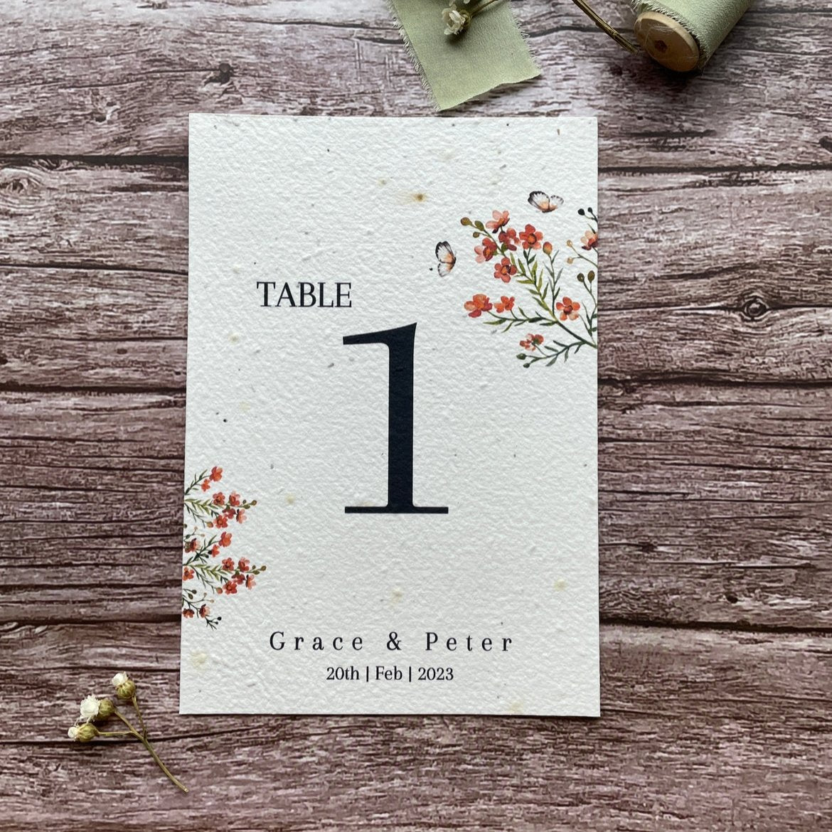 plantable seed paper wedding table number or name cards in burnt orange theme, front close-up view with floral design on wooden background, eco-friendly, alakartcreations
