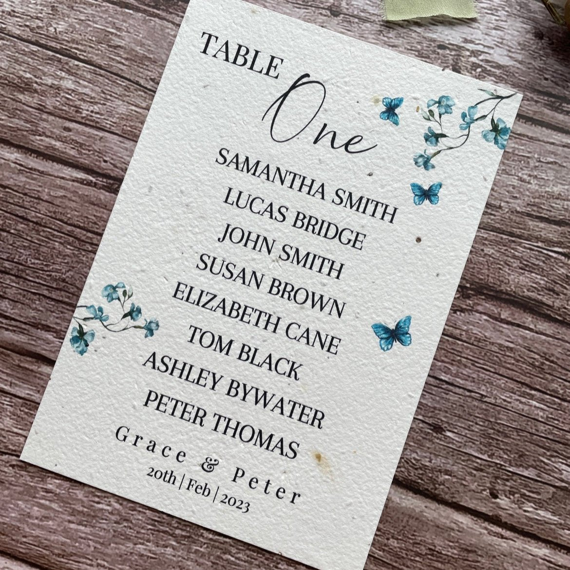 plantable seed paper wedding table seating plan in dusty blue theme, angled right view with floral design on wooden background, eco-friendly, alakartcreations