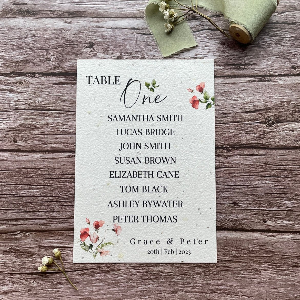 plantable seed paper wedding table seating plan in sweet pea theme, front view with floral design on wooden background, eco-friendly, alakartcreations