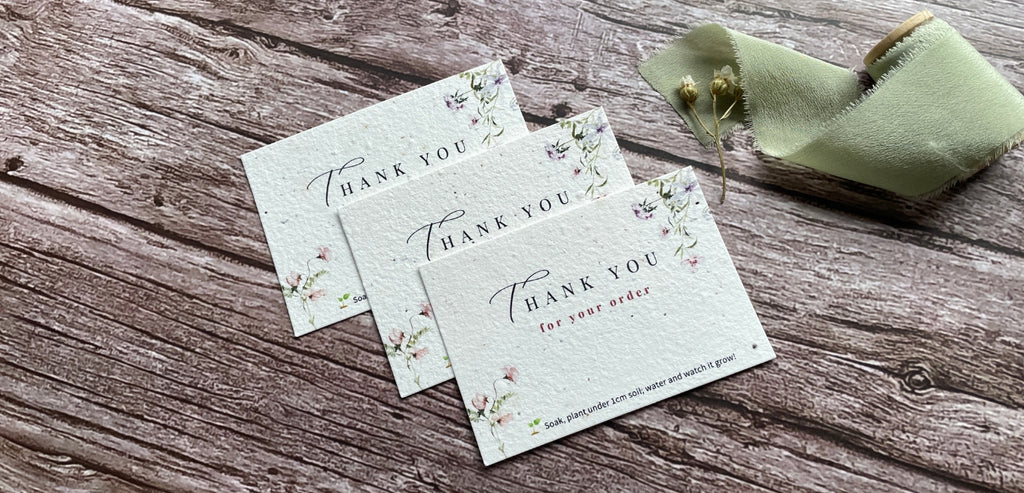Plantable thank you cards, laid out on a wooden backdrop, promoting A La KArt Creations pre-designed stationery range.
