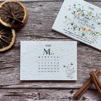 Seed paper 2026 calendar cards on a wooden surface with dried oranges and cinnamon sticks.