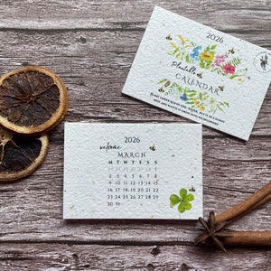 Two seed paper calendars on a wooden surface with dried oranges and twine.