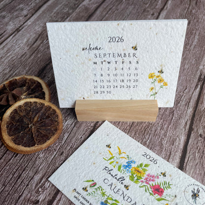 Two seed paper calendars with floral designs in a wooden stand.