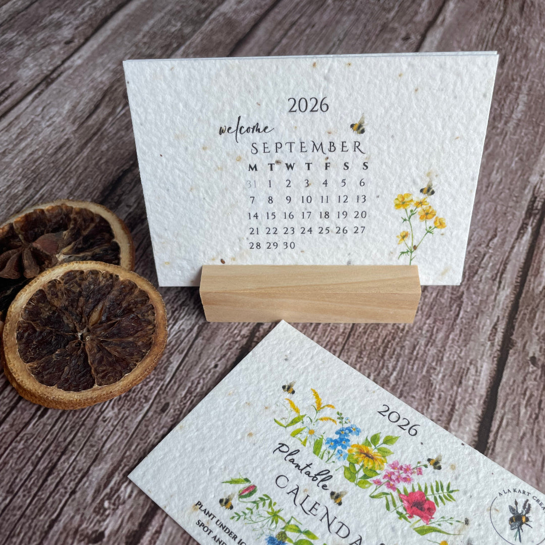 Two seed paper calendars with floral designs in a wooden stand.