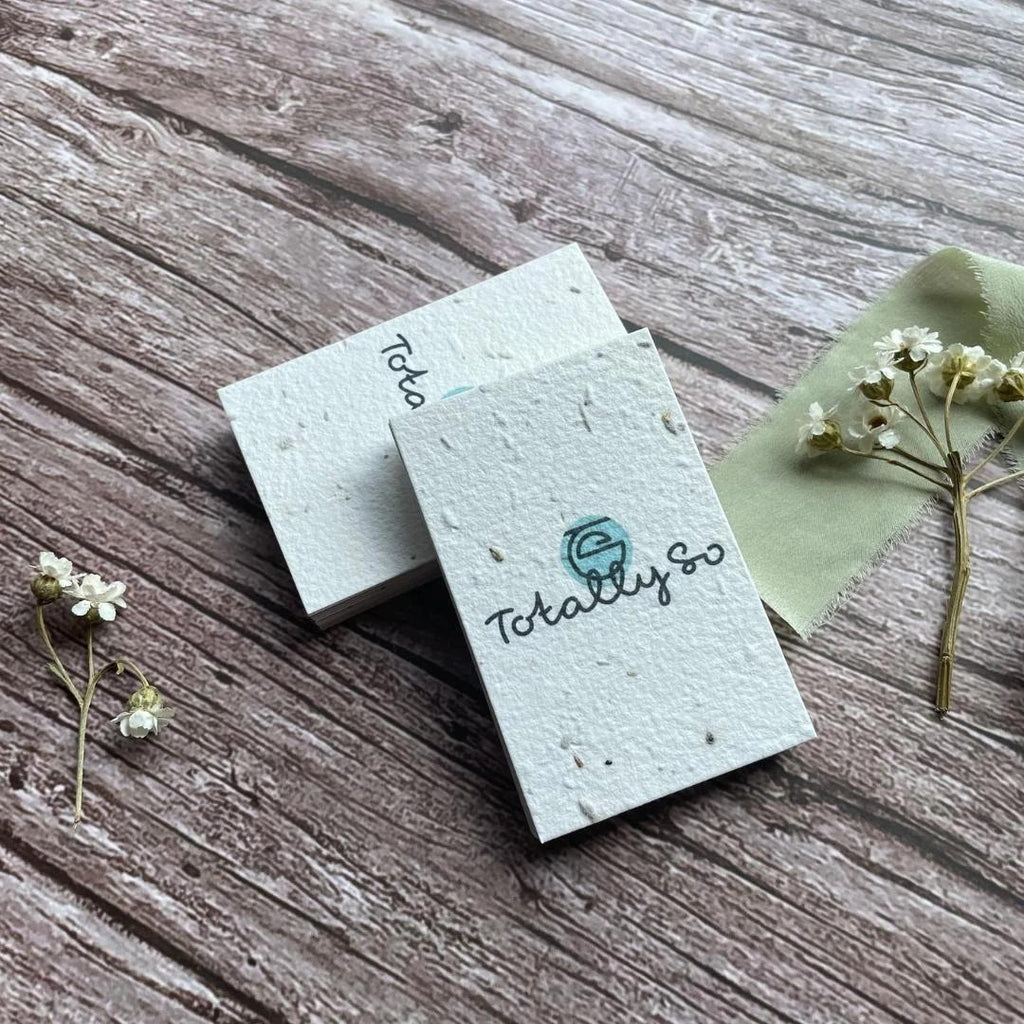 A La KArt Creations business cards, made with plantable wildflower seed paper, laid out on a wooden backdrop with dried flowers.
