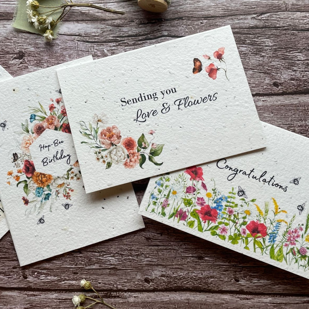 A range of A La KArt Creations plantable greeting cards, laid out on a wooden backdrop with dried flowers.