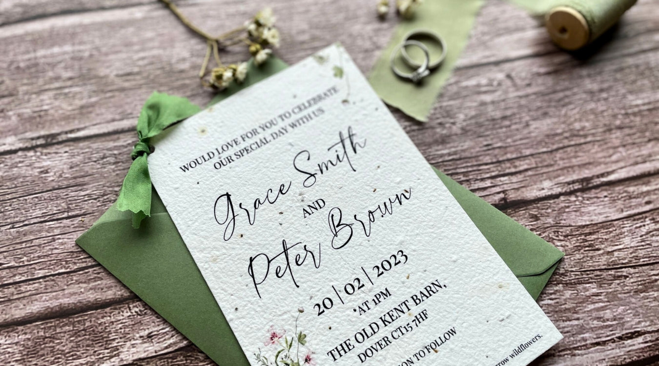 The Spring Green themed Wedding Invitation, placed on a wooden board with wedding rings and dried flowers. 
