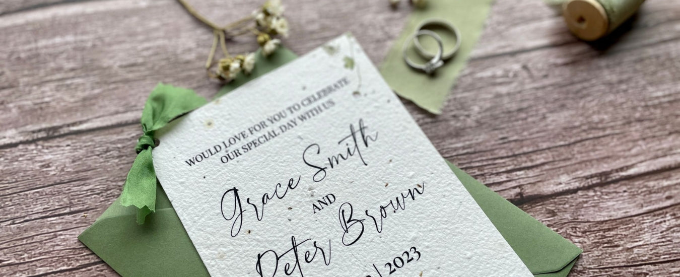One of A La KArt Creations plantable wedding invitations, featuring the Spring Green theme. Showcased alongside silver wedding rings, flowers, and organic cotton.