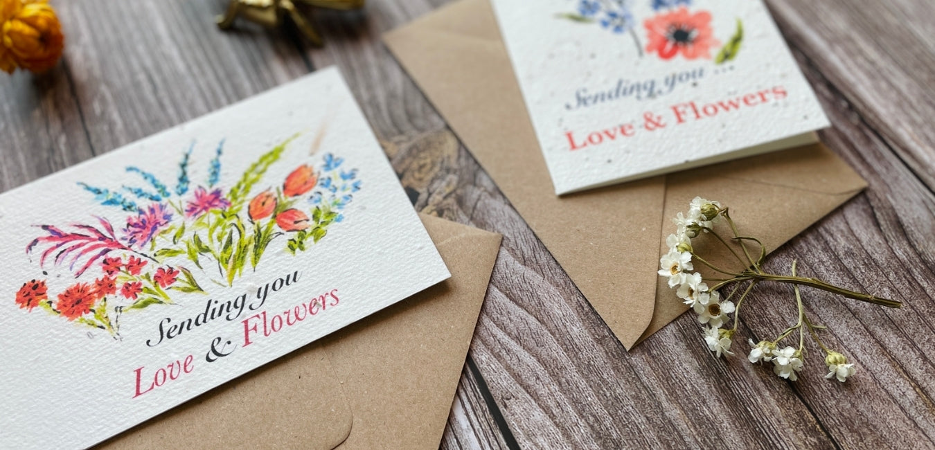 Plantable greeting cards showcased on a wooden backdrop surrounded by wildflowers