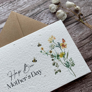 angled close up personalised plantable mother's day card with buzzing bees and wildflowers, feat. "Hap-Bee Mother's Day" message