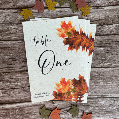 Autumn-themed plantable table number card with leaf designs on a wooden surface