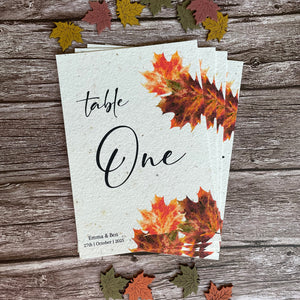 Autumn-themed plantable table number card with leaf designs on a wooden surface