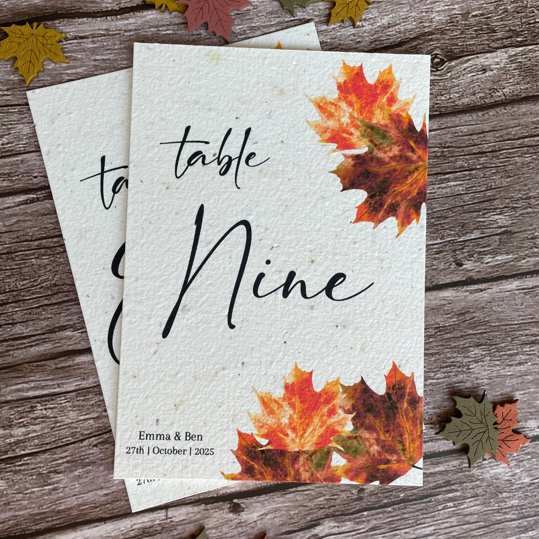 Autumn-themed table number with leaf decorations on a wooden surface made from plantable paper