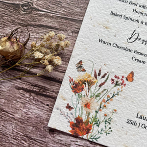 Autumn wedding Menu with floral design and text on a wooden surface made from seed paper