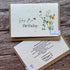Two planrable greeting cards on a wooden surface, one with floral design and &