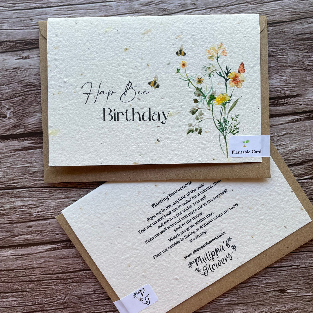 Two planrable greeting cards on a wooden surface, one with floral design and 'Happy Birthday' text