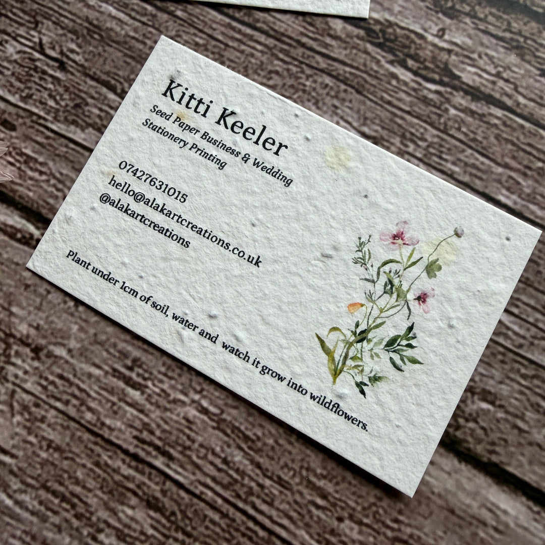 seed paper business cards with floral  design on a wooden surface.