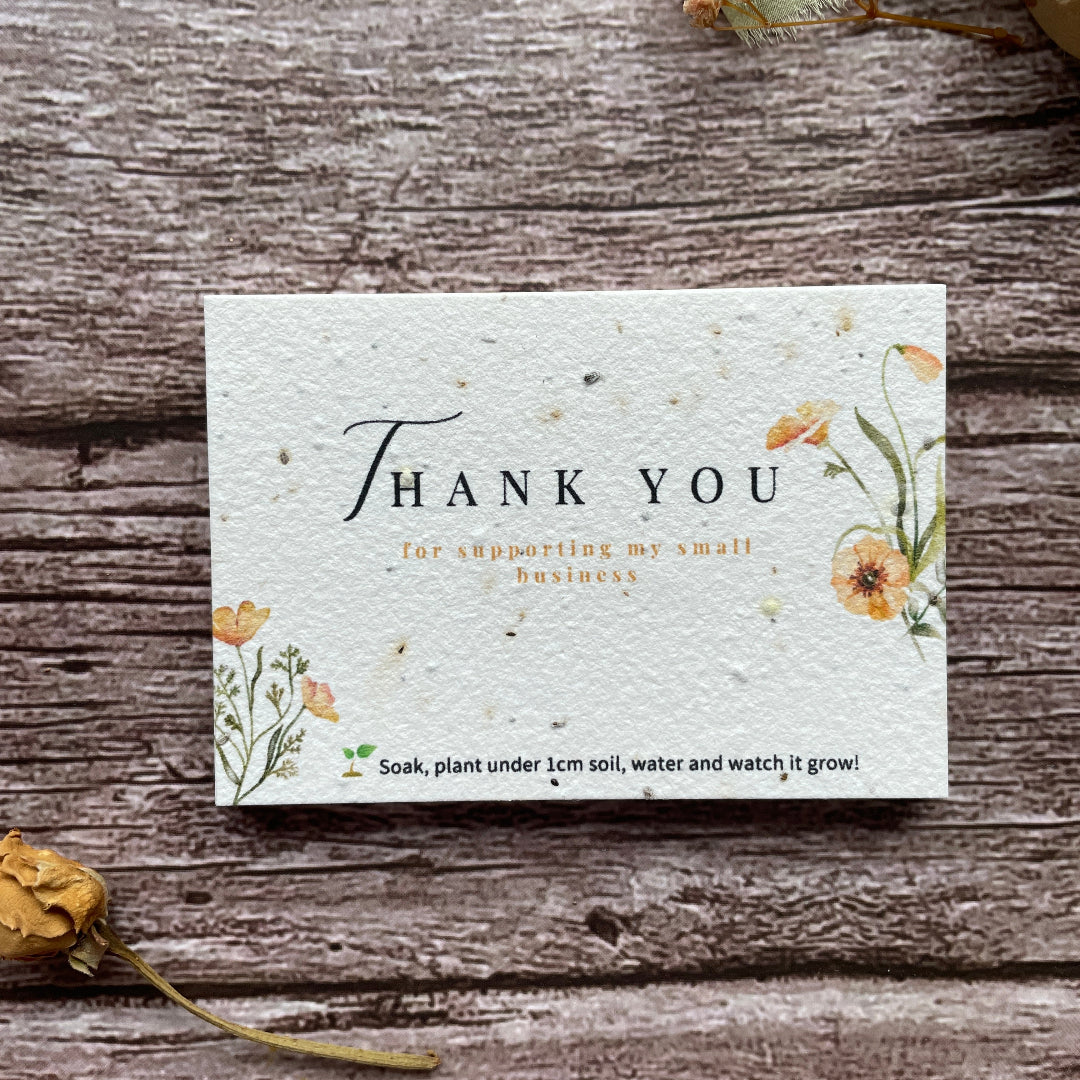 Seed paper thank you card with floral design on a wooden surface