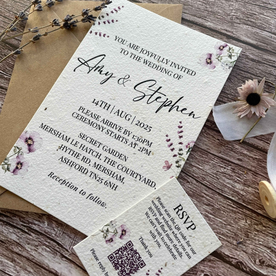 personalised plantable wedding invitations lilac theme, angled view with eco-friendly brown kraft envelope, and qr code rsvp on wooden background