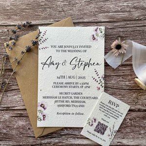 personalised plantable wedding invitations in lilac theme, front view with eco-friendly brown kraft envelope, and qr code rsvp on wooden background