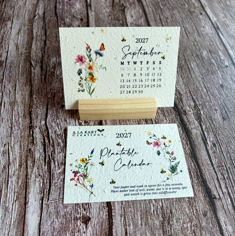 A handmade seed paper calendar card set displayed on a rustic wooden surface, featuring a September 2027 calendar page and a front cover for a &