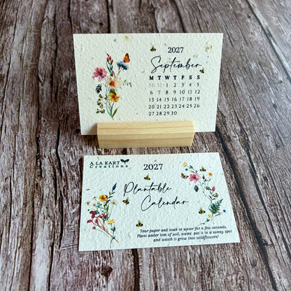 A handmade seed paper calendar card set displayed on a rustic wooden surface, featuring a September 2027 calendar page and a front cover for a &