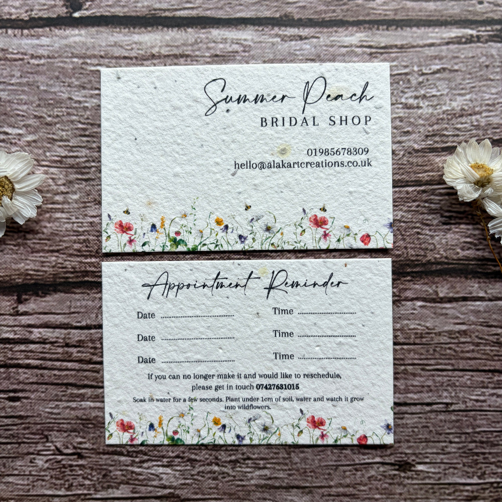 Two appointment reminder cards with floral designs on a wooden surface.