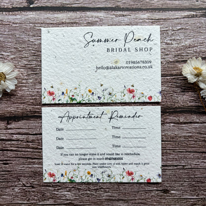 Two appointment reminder cards with floral designs on a wooden surface.