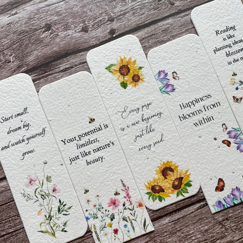 Decorative plantable bookmarks with floral designs and text on a wooden surface