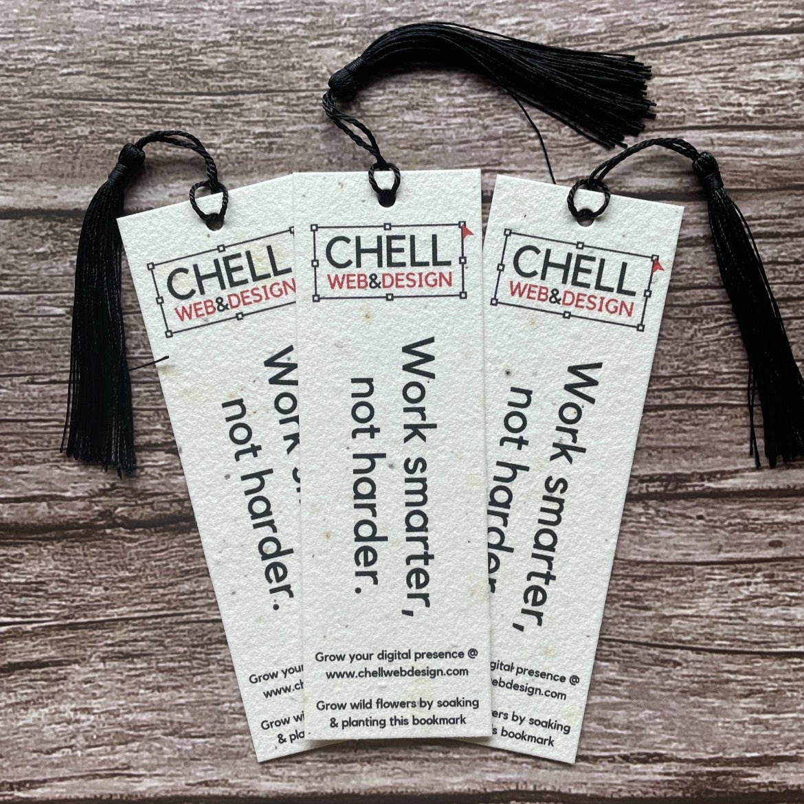 Three plantable bookmarks with the Chell Design branding, featuring a seed paper construction with a black tassel on top. Each bookmark has text that says &