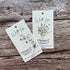 Two plantable floral gift tags on a wooden surface