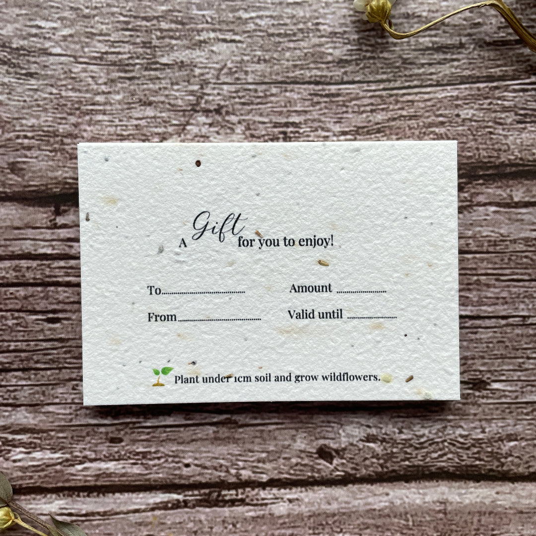 Seed paper gift card on a wooden surface with plantable seeds.