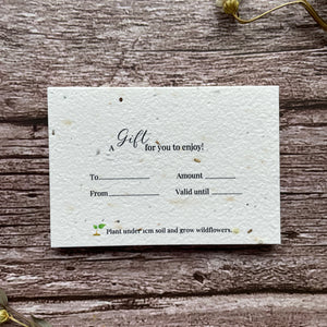 Seed paper gift card on a wooden surface with plantable seeds.
