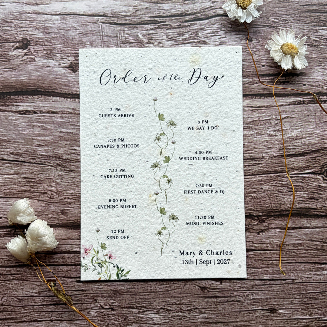 plantable seed paper wedding order of the day card on wooden surface with botanical design