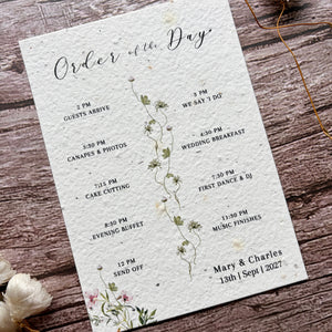 Wedding order of the day card with floral design on a wooden surface