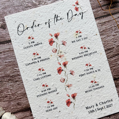 Wedding seed paper order of the day card with floral design on a wooden surface