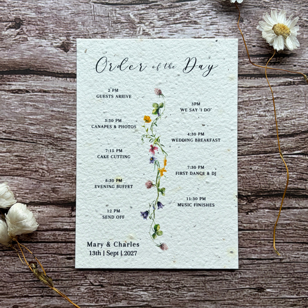 Wedding order of service on a plantable seed paper on a rustic wooden background with flowers